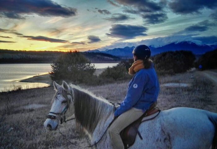 mujer encima caballo mirando el atardecer