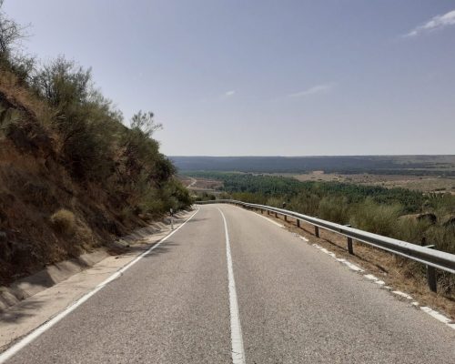 Vista de una carretera recta que serpentea a través de un paisaje montañoso.