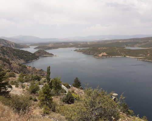 Lago visto desde una perspectiva elevada, rodeado de montañas y vegetación.