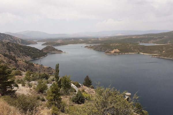 Lago visto desde una perspectiva elevada, rodeado de montañas y vegetación.