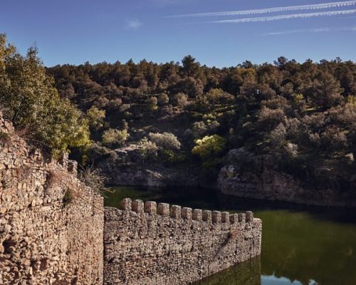 Panorámica del castillo de Buitrago, rodeado por un lago.
