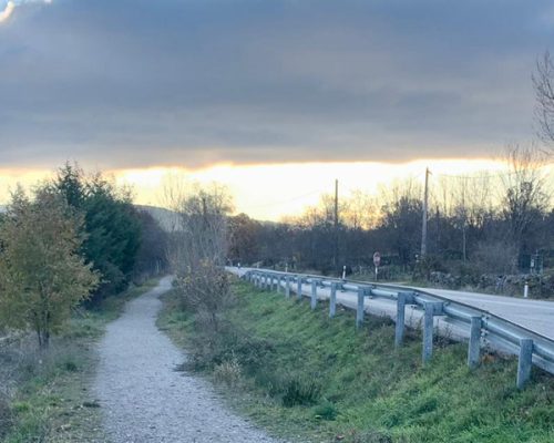 Vista de un camino de tierra que corre paralelo a una carretera asfaltada.