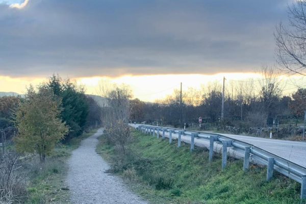 Vista de un camino de tierra que corre paralelo a una carretera asfaltada.