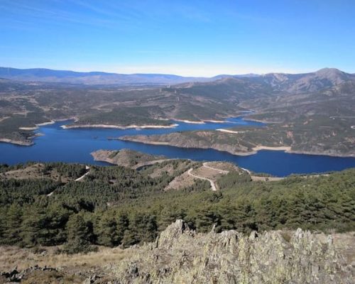 Perspectiva elevada de un lago rodeado de montañas y paisajes naturales.