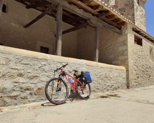 Vista de la iglesia de Prádena con una bicicleta apoyada en su fachada.
