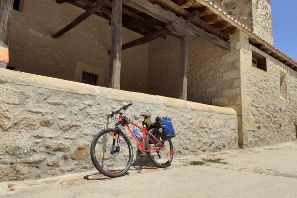 Vista de la iglesia de Prádena con una bicicleta apoyada en su fachada.