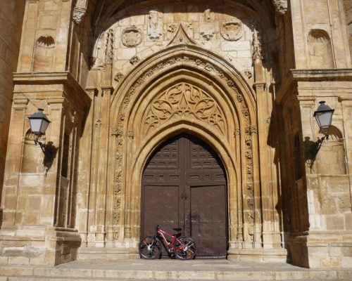 Vista de la iglesia de Torrelaguna con una bicicleta apoyada en su fachada.