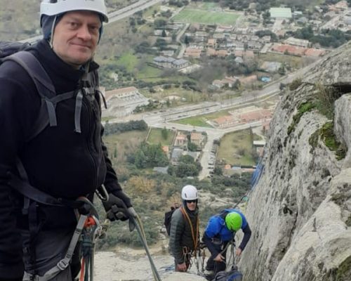 Escalador ascendiendo una roca en un paisaje montañoso.
